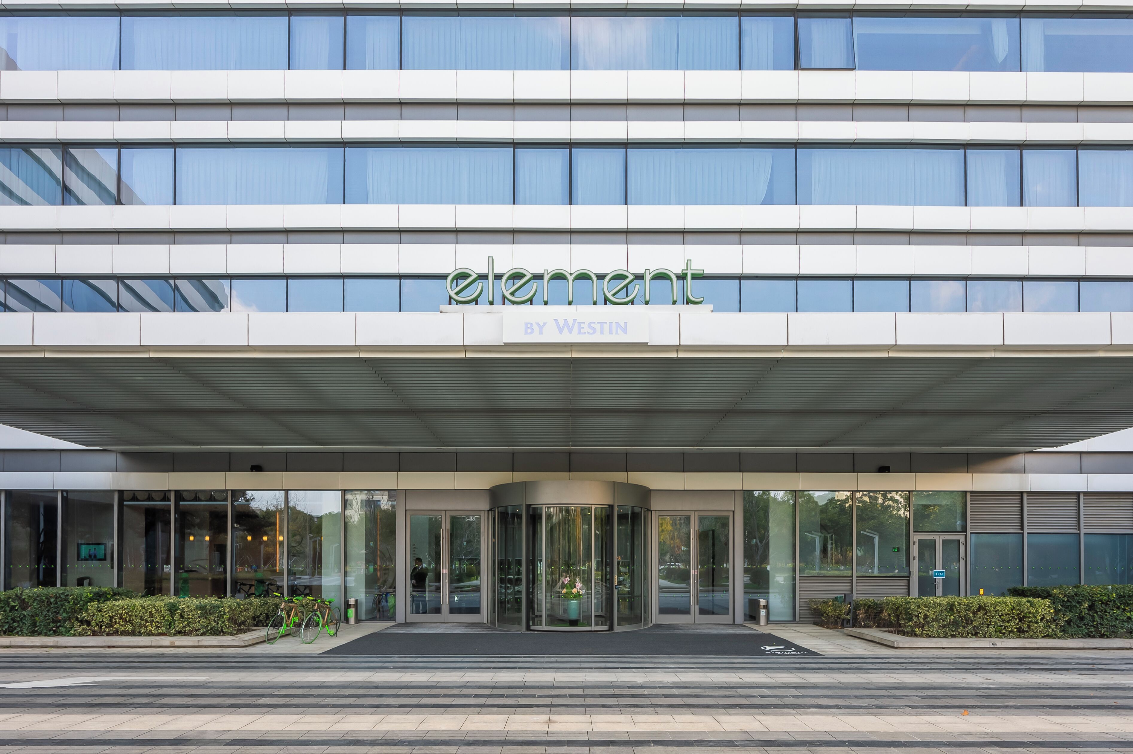 A modern building with a glass facade, a revolving door entrance, and the name "element by Westin" displayed above.