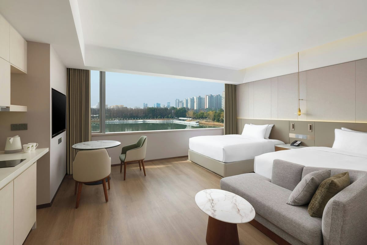 Una habitación de hotel moderna con una cama grande, un sofá, una mesa de comedor y un televisor.