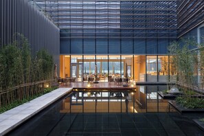 A modern indoor pool area with a glass ceiling, seating by the pool, and a view of the cityscape. - Element Suzhou Science and Technology Town (Suzhou)