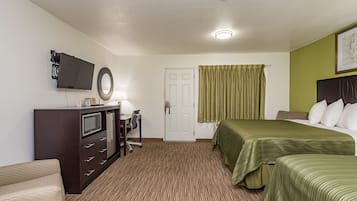 Una habitación de hotel con una cama, un escritorio con una silla, un televisor y una puerta.