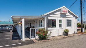 Motel Sundowner con entrada cubierta, estacionamiento y un pequeño jardín con flores.