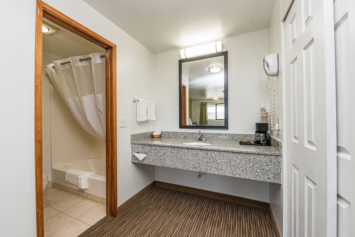 Baño con ducha, inodoro, lavamanos y espejo.