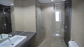Een moderne badkamer met een douchecabine van glas, een grote spiegel en een wit wastafelmeubel.