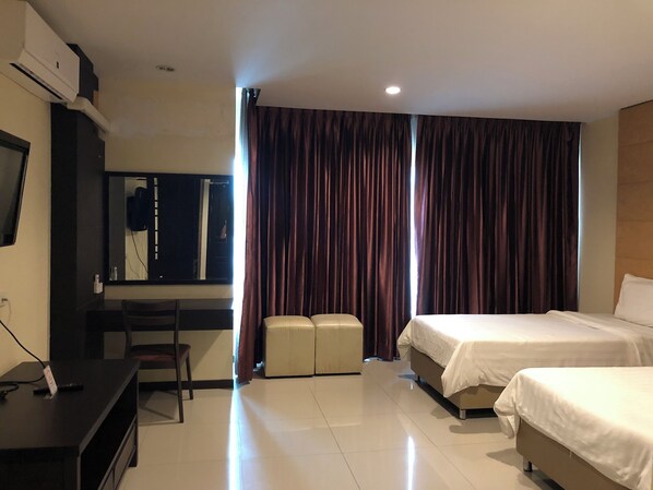 A hotel room with a bed, a desk, a chair, a television, and a large window with curtains.