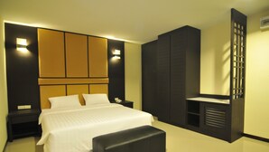 Een moderne slaapkamer met een groot bed, een bankje, een nachtkastje en inbouwkasten.