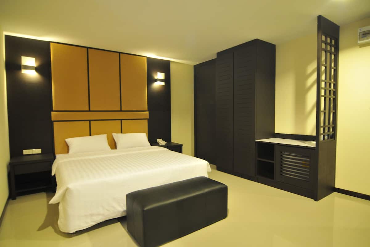 Ein modernes Schlafzimmer mit einem großen Bett, einer Bank, einem Nachttisch und Einbauschränken.