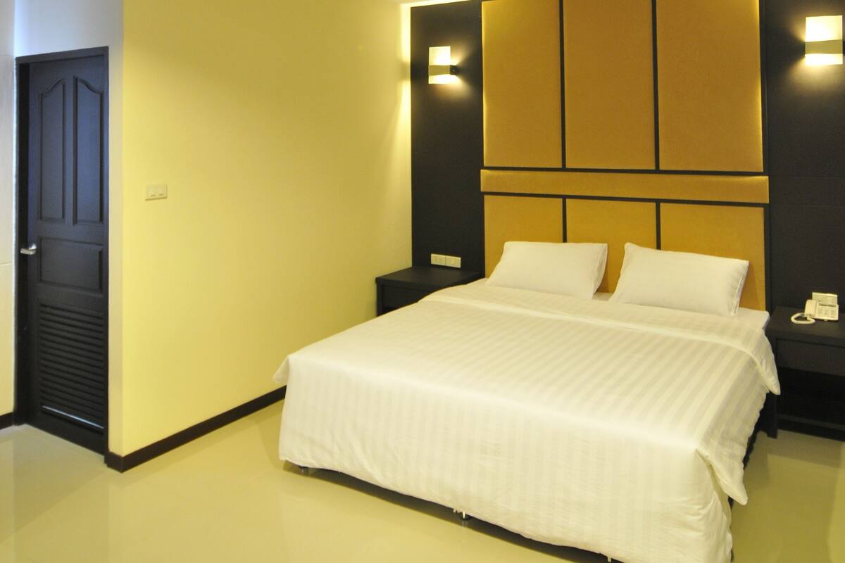 Ein modernes Hotelzimmer mit einem großen Bett, einem Nachttisch und einer wandmontierten Lampe.