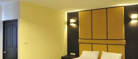 Una habitación de hotel moderna con una cama grande, una mesita de noche y una lámpara fijada a la pared.