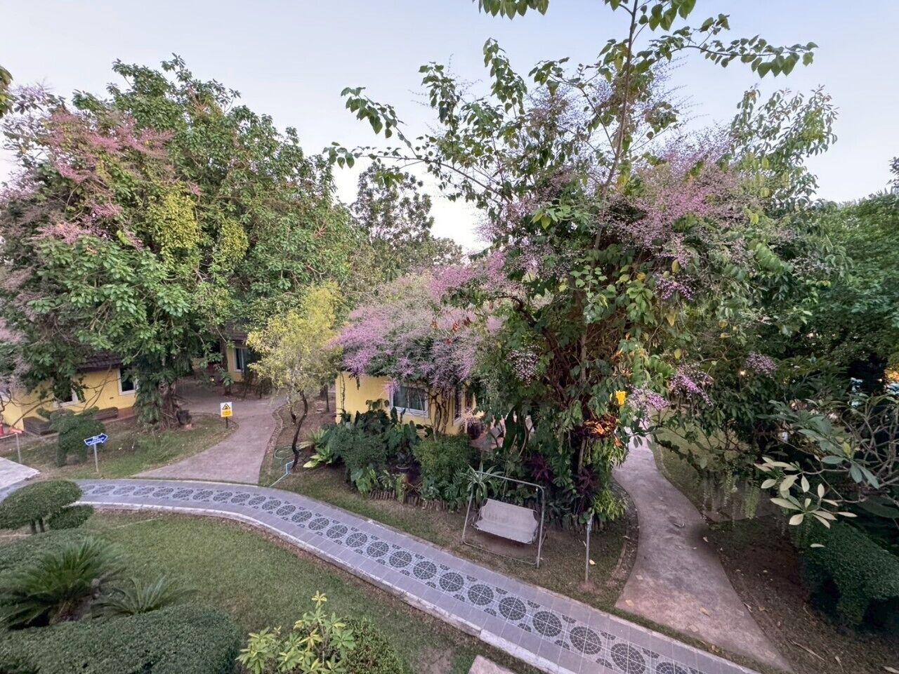 A garden pathway leading to a yellow building with a small porch.