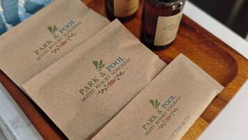 Três sacos de papel castanhos com a inscrição "Park & Pool Hotel Resort Nongkhai" sobre uma bandeja de madeira.