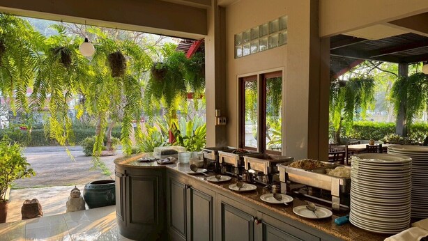 Uma cozinha com uma ilha grande, vista para um jardim e uma janela com persianas.