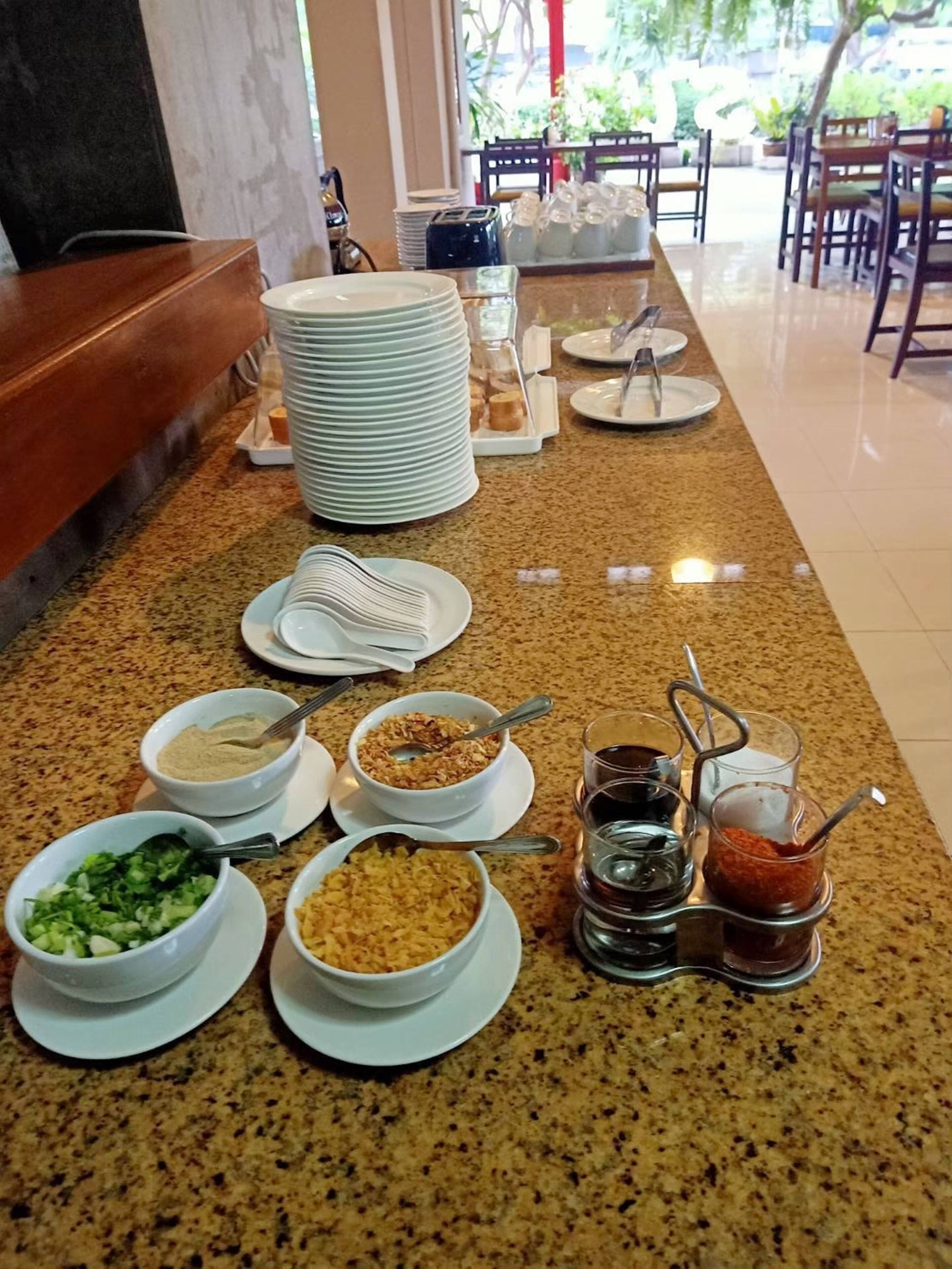 Disposição de buffet com diversos alimentos e acompanhamentos em uma bancada.