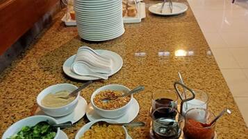 Disposição de buffet com diversos alimentos e acompanhamentos em uma bancada.