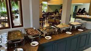 Uma área de buffet com várias estações de comida, um canto de café e pratos empilhados.