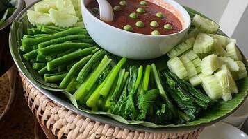 Une présentation de plats comprenant un bol de sauce et divers légumes disposés sur un plateau en osier.