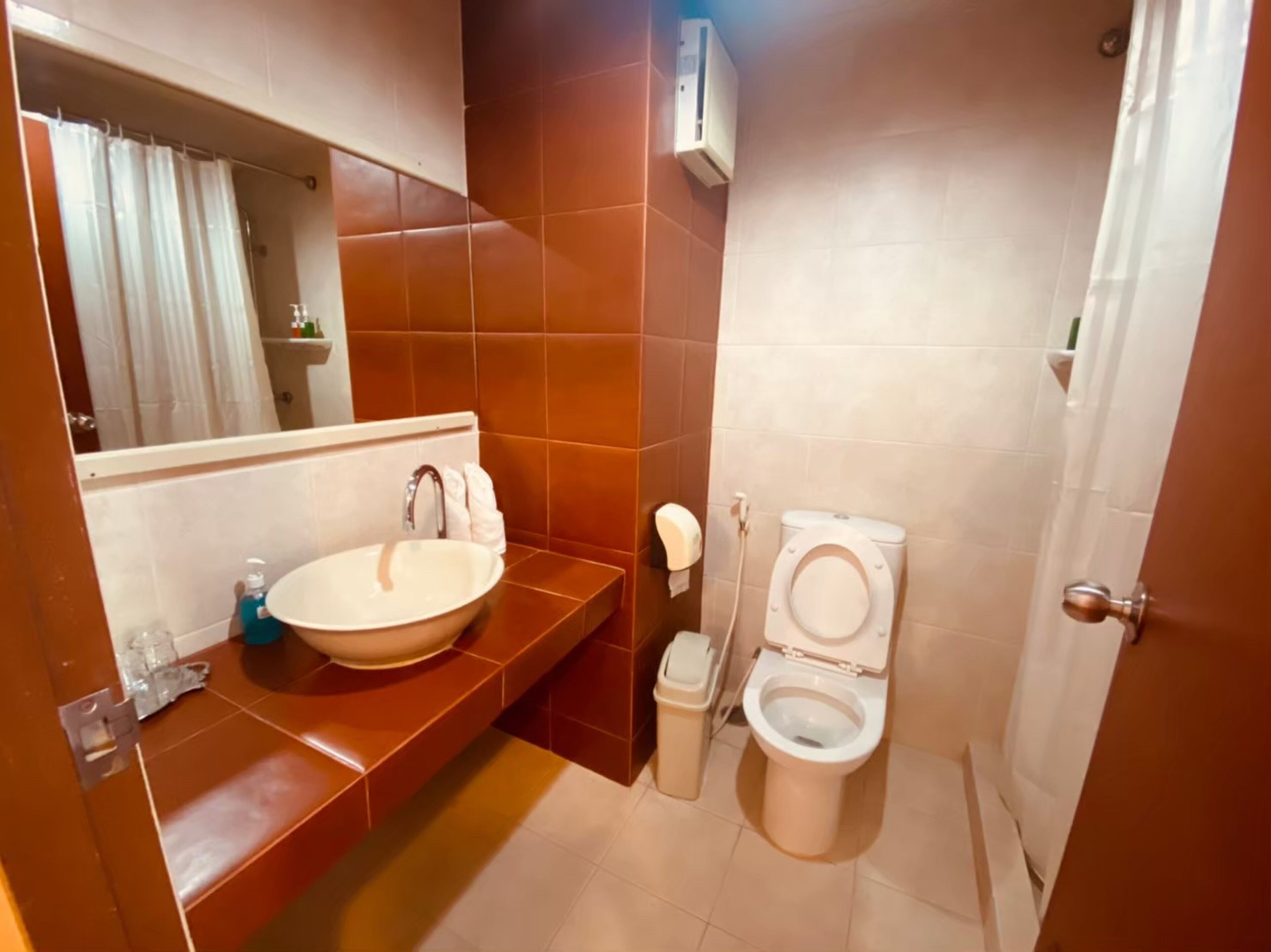 Une salle de bain équipée d’un lavabo, d’un miroir, de toilettes et d’un distributeur de serviettes.