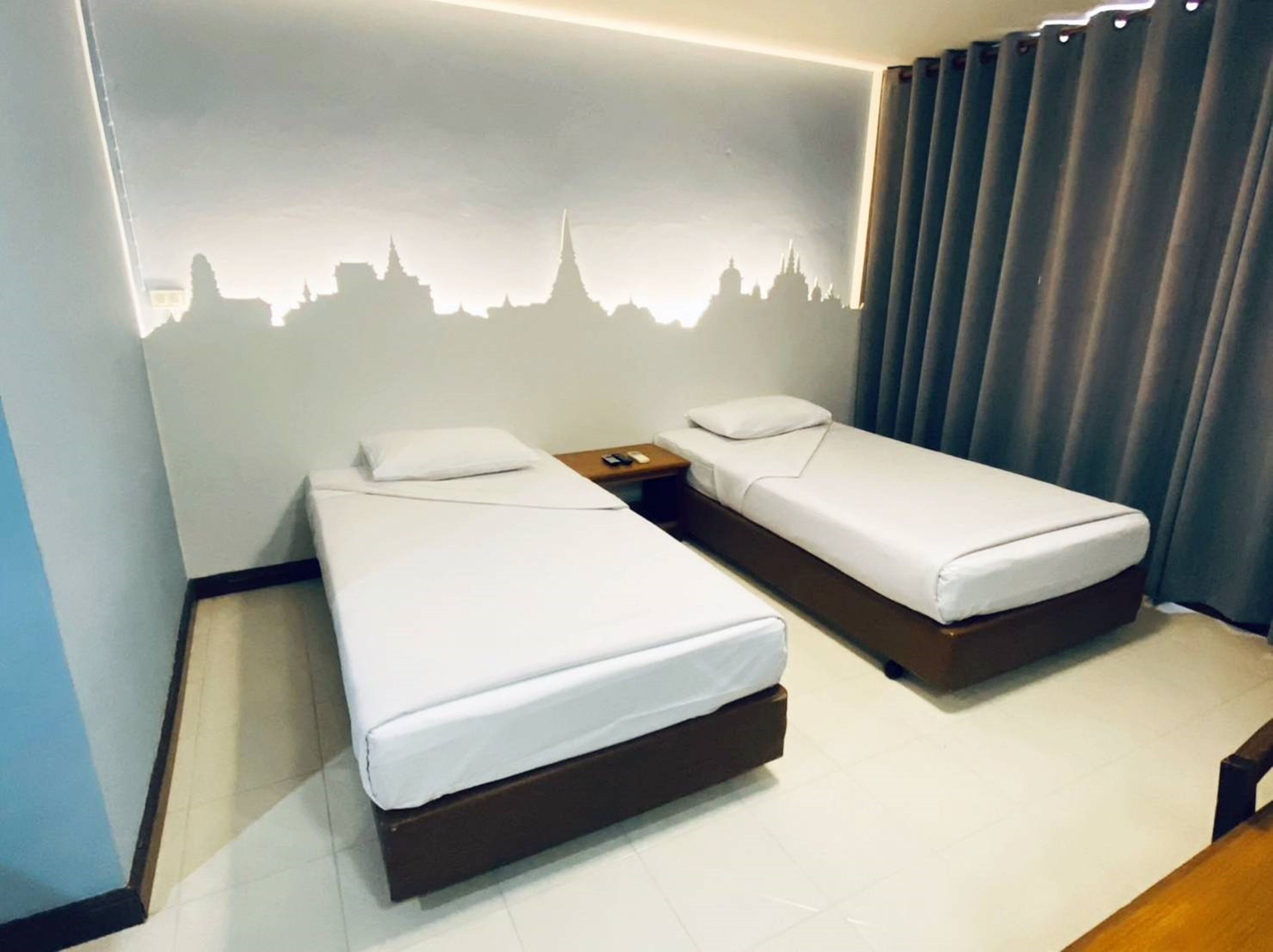 Una habitación de hotel con dos camas individuales, una mesita de noche y un mural en la pared.