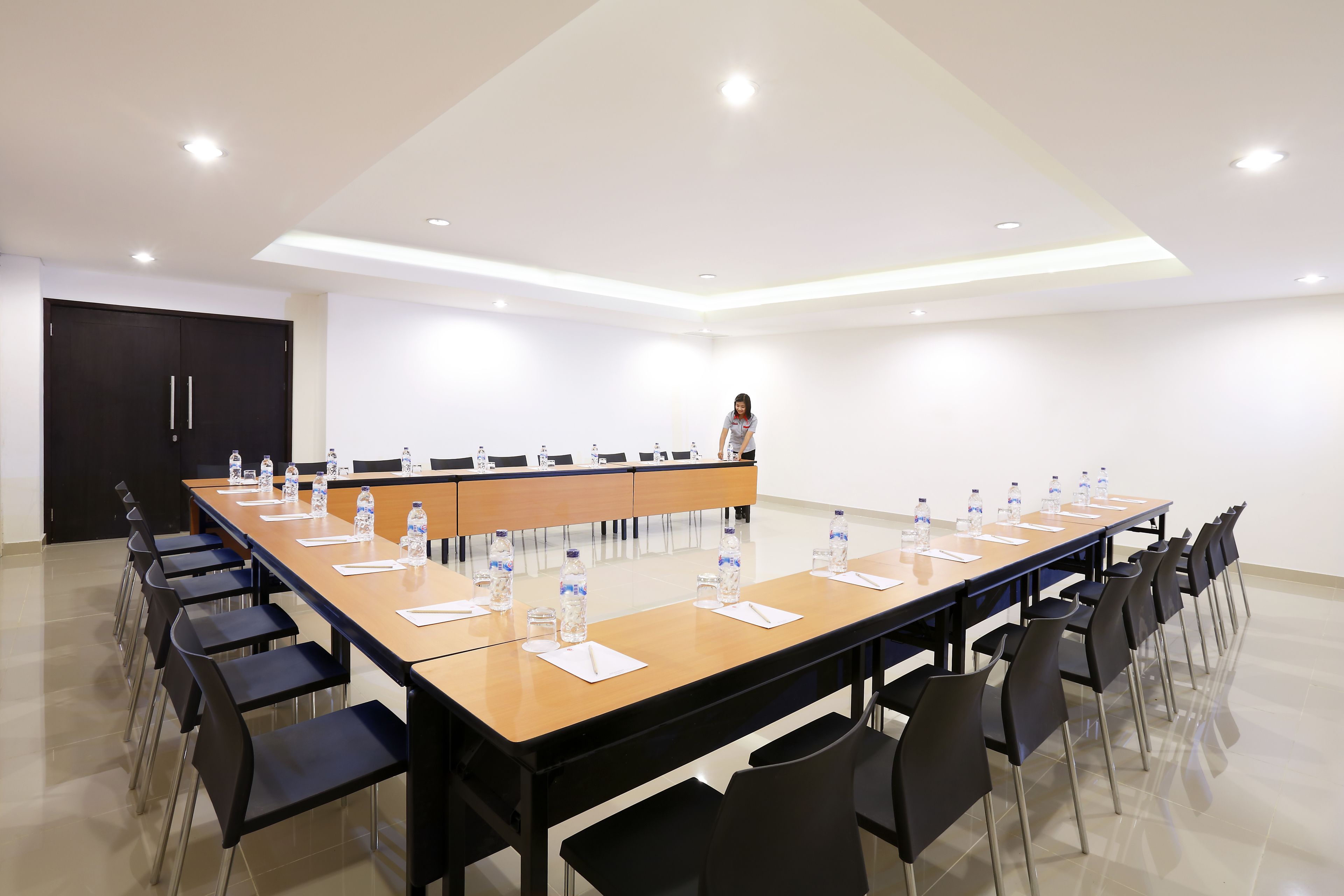 A conference room with a long table, chairs, water bottles, and a podium.
