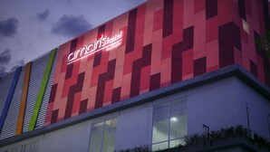 A modern hotel building with a prominent signage for "Amc's hotel by senfika" against a twilight sky.