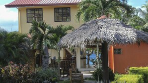 A two-story building with a thatched roof structure, surrounded by lush greenery and palm trees. - Isla Hayahay Beach Resort and Restaurant (Calape)