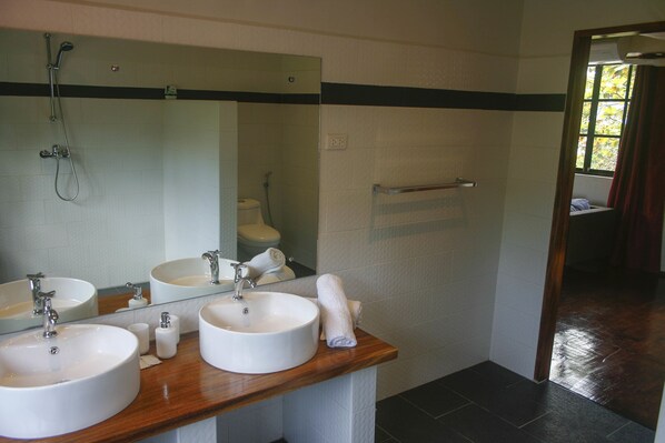 Un baño con dos lavamanos, ducha y espejo.