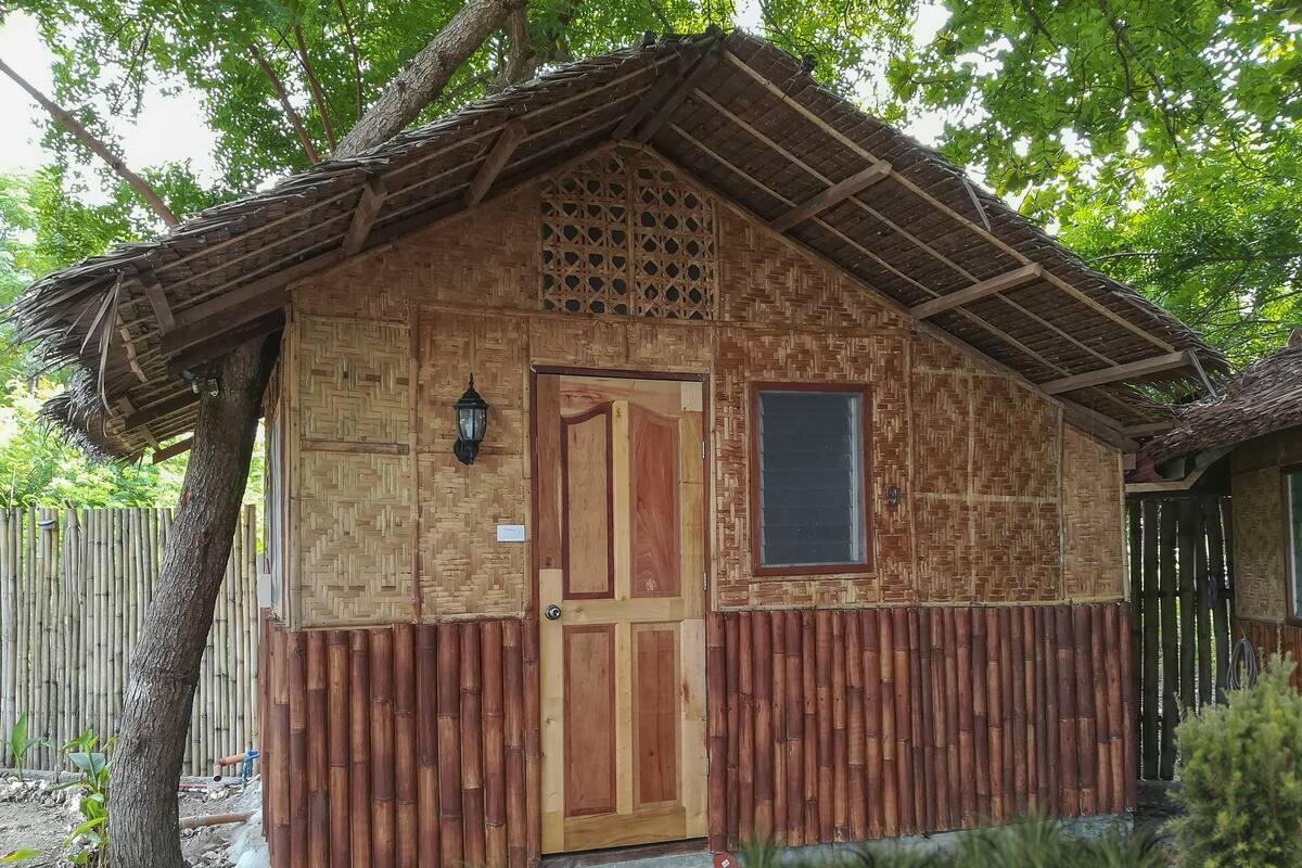 A small, rustic wooden building with a thatched roof, a wooden door, and a window.