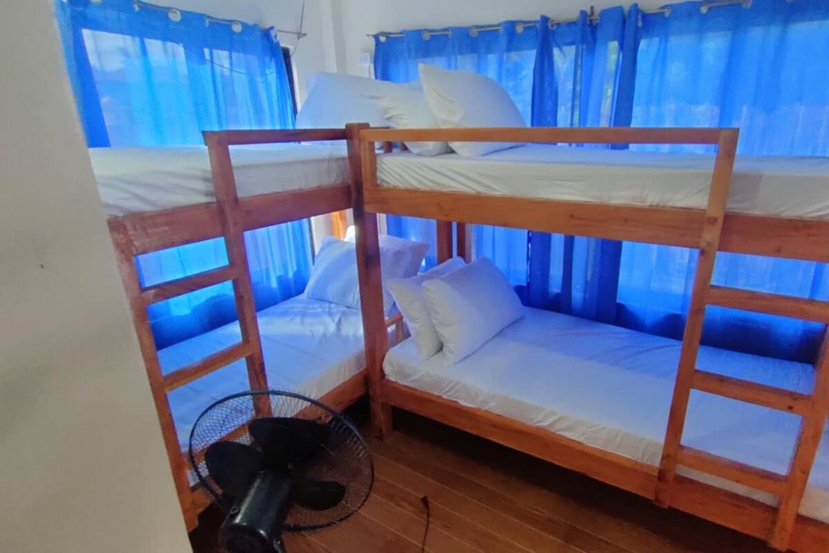 A bunk bed room with a fan and blue curtains.