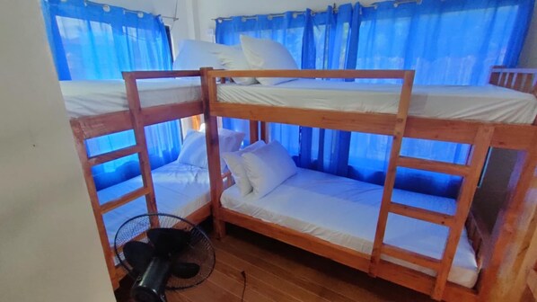 A bunk bed room with a fan and blue curtains. - Isla Hayahay Beach Resort and Restaurant (Calape)