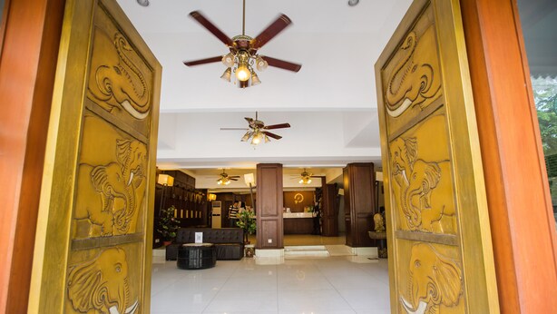 A reception area with a ceiling fan, a reception desk, and a seating area with sofas. - Chiang Roi 7 Days Inn (Chiang Mai)