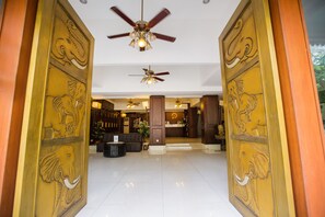 A reception area with a ceiling fan, a reception desk, and a seating area with sofas. - Chiang Roi 7 Days Inn (Chiang Mai)