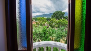 A view through a window with a white balustrade, looking out to a green landscape with trees and mountains in the distance. - Chiang Roi 7 Days Inn (Chiang Mai)