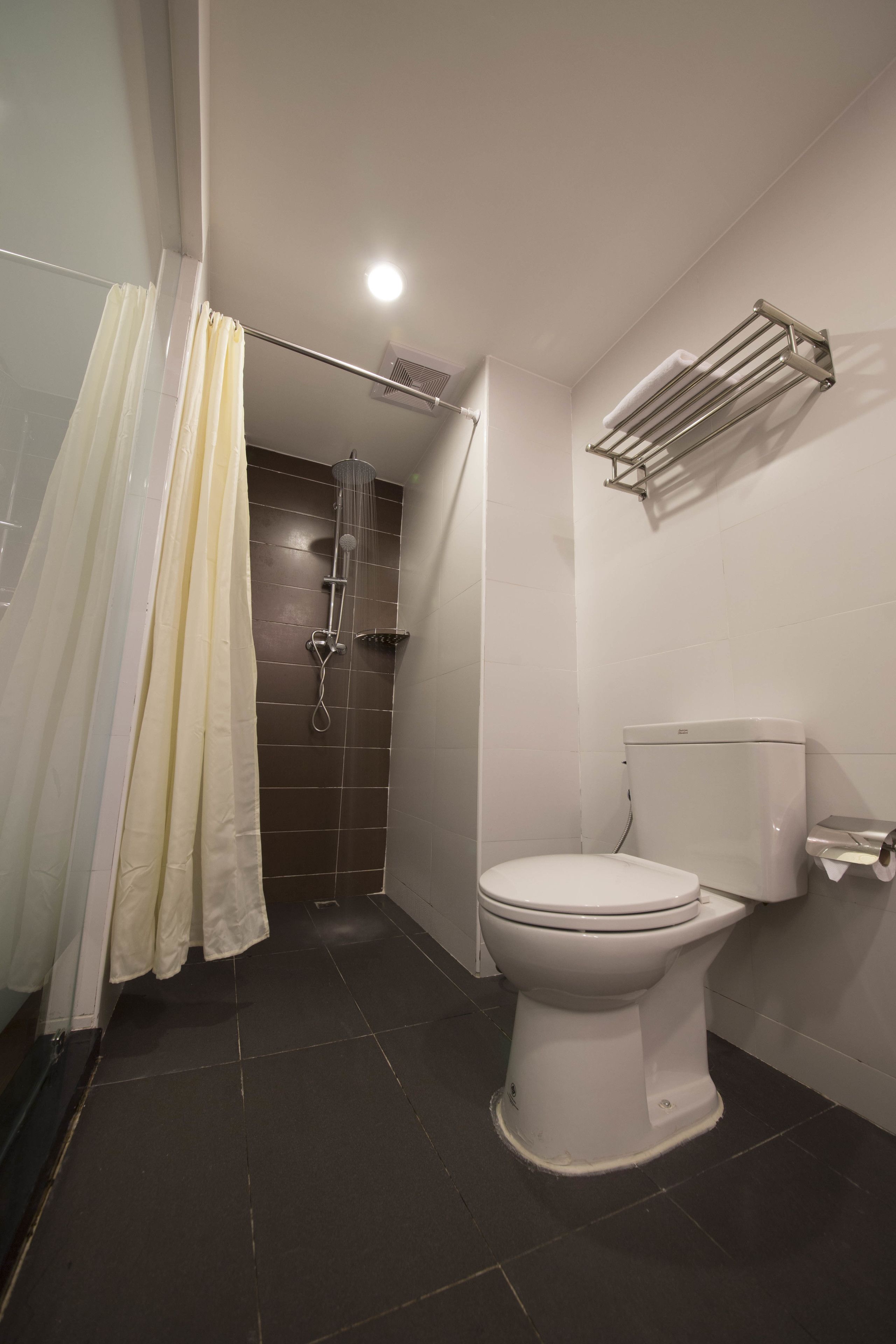 A bathroom with a shower, toilet, and towel rack.