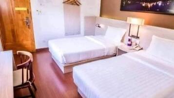 A hotel room with two beds, a desk, and a chair.