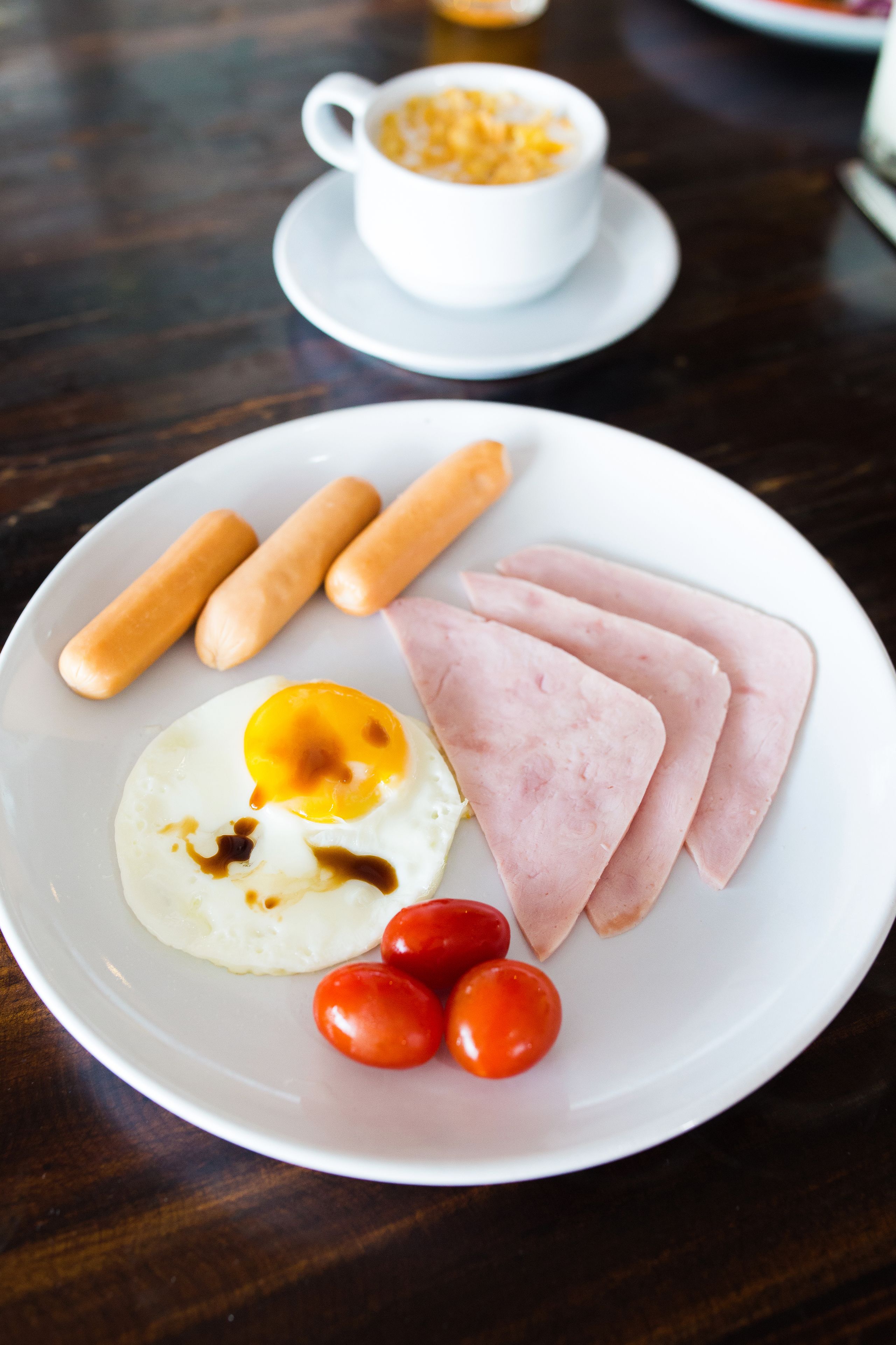 Un plato con jamón, huevos y tomates sobre una mesa de madera.