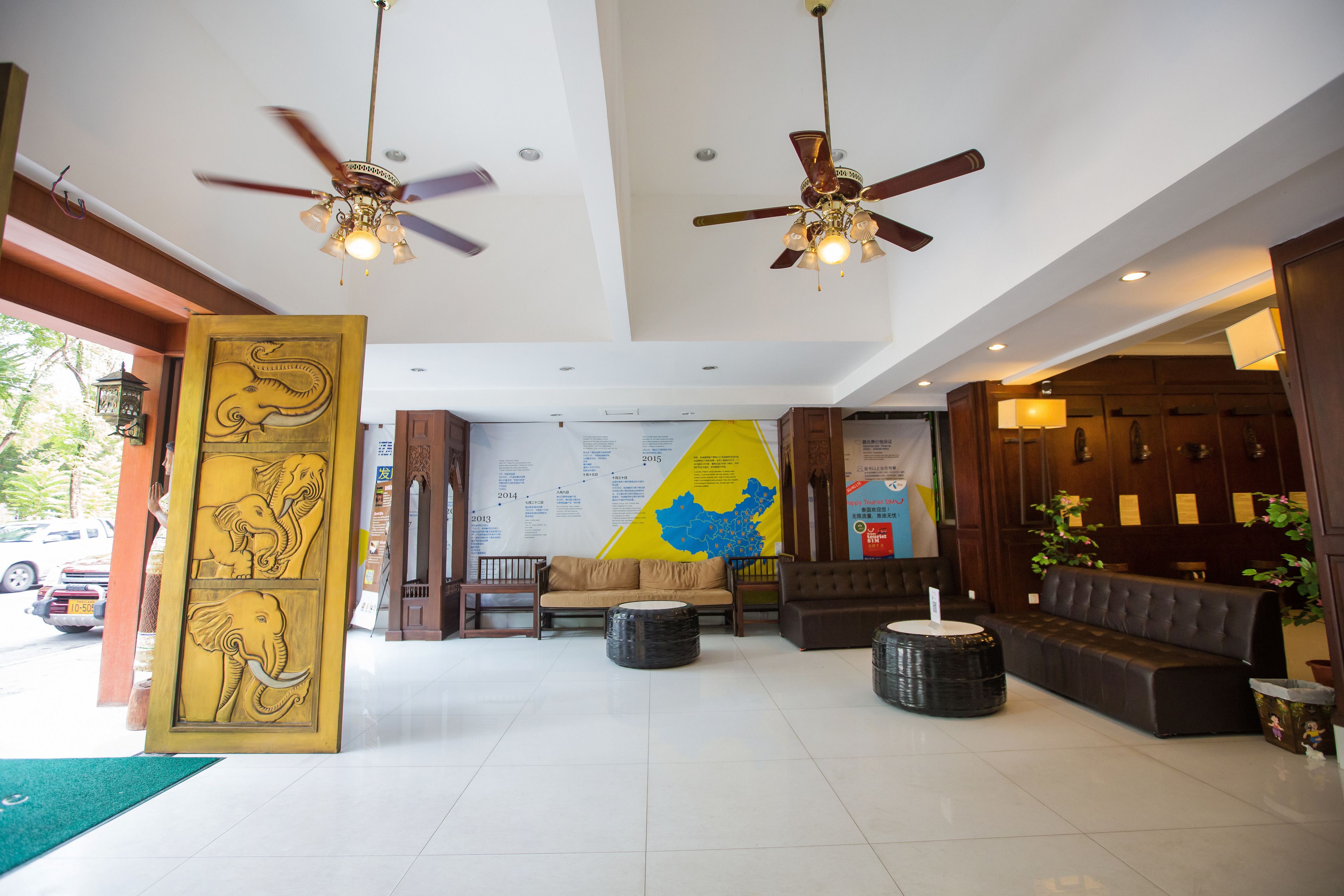 A lobby with a reception desk, seating area, ceiling fans, and a large wall map.