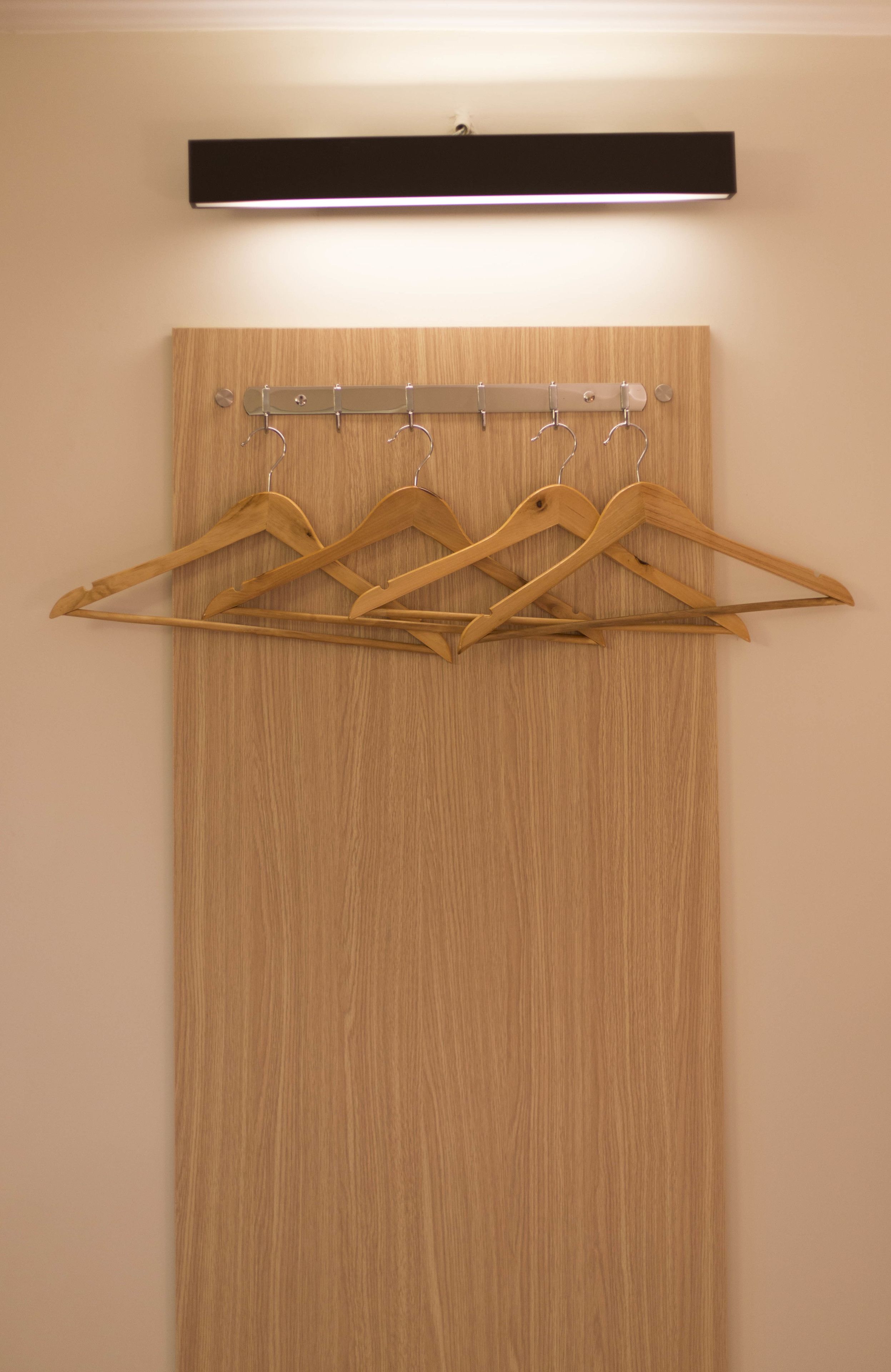 A wooden wardrobe with a light wood finish and a black shelf above it.