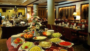 A buffet setup with various food items and a floral centerpiece.