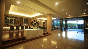 A modern lobby with a reception desk, seating area, and a view of the outdoors.