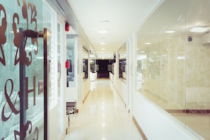 A clean, well-lit hallway with glass doors and a polished floor, leading to a dark interior. - House and Home Residence (Chiang Mai)
