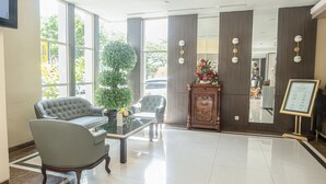 A lobby with a large window, a reception desk, and a seating area with two armchairs and a coffee table. - Horison Kendari (Kendari)
