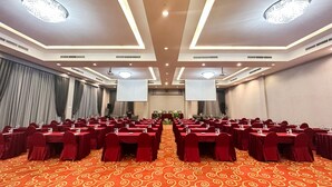 A conference room with rows of tables, a large screen, and a carpeted floor. - Horison Kendari (Kendari)