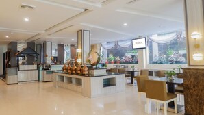 A modern hotel lobby with a central island, seating area, and a large window with plants. - Horison Kendari (Kendari)