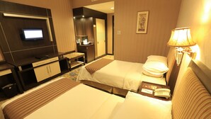 A hotel room with two beds, a desk with a flat-screen TV, a lamp, and a small table with a phone and notepad. - Horison Kendari (Kendari)