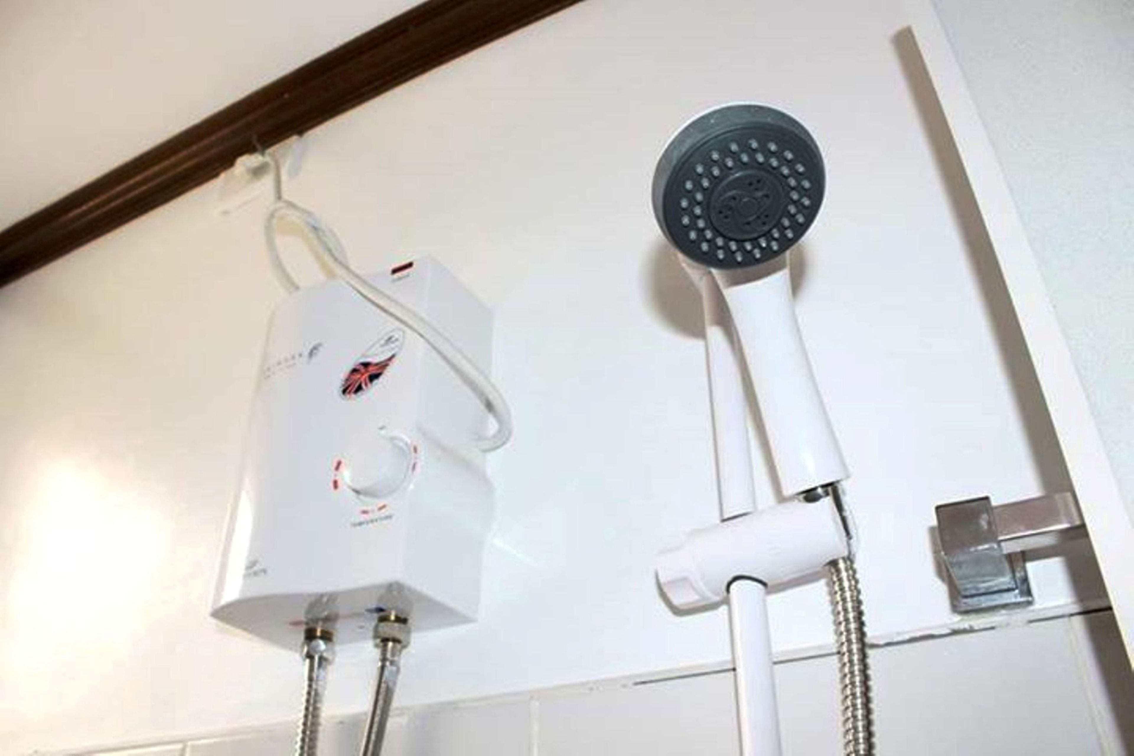 A shower unit with a control panel and a handheld showerhead mounted on a wall.