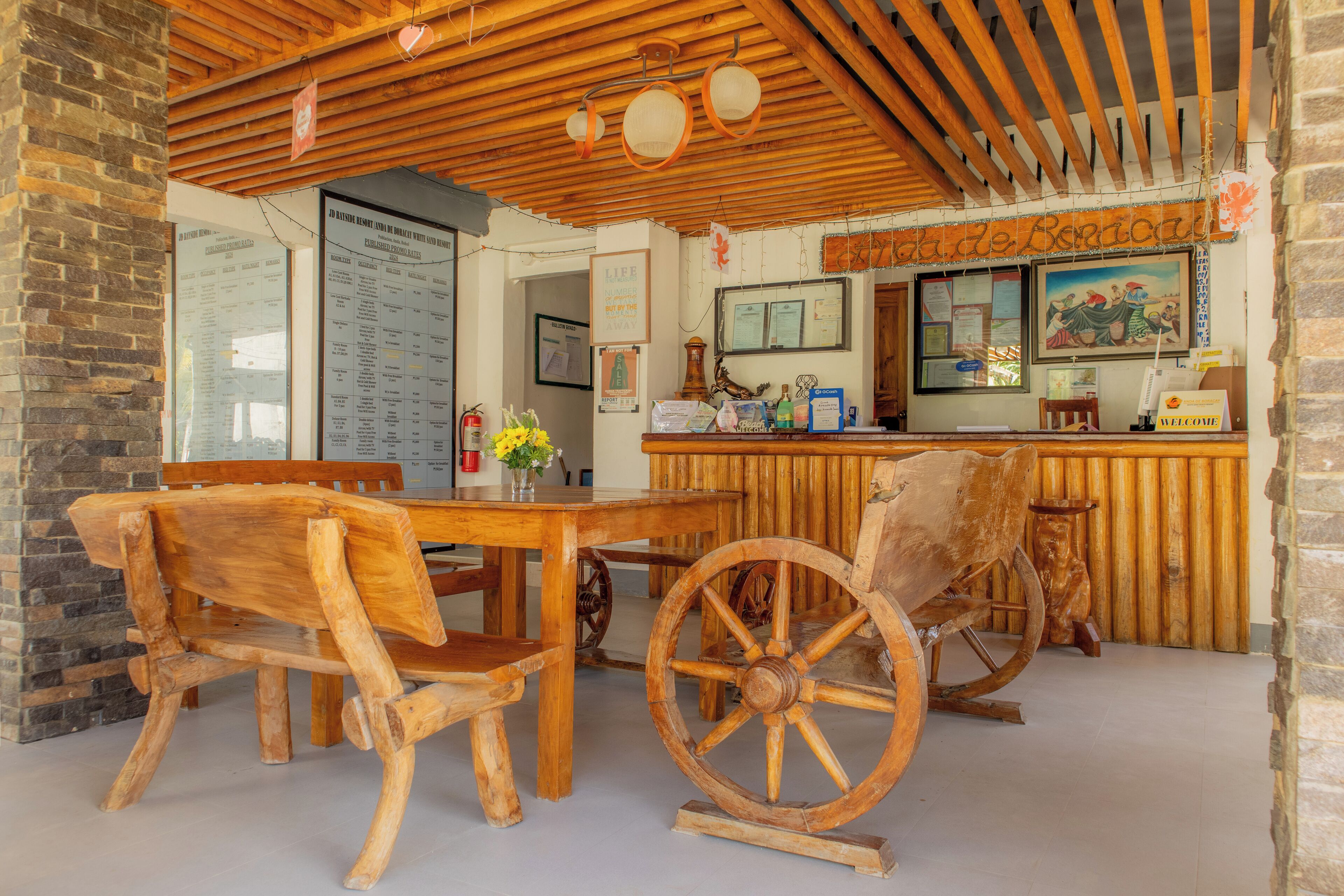 A rustic wooden interior with a wooden table and chairs, a vintage wooden cart, and a wooden counter with a menu board.