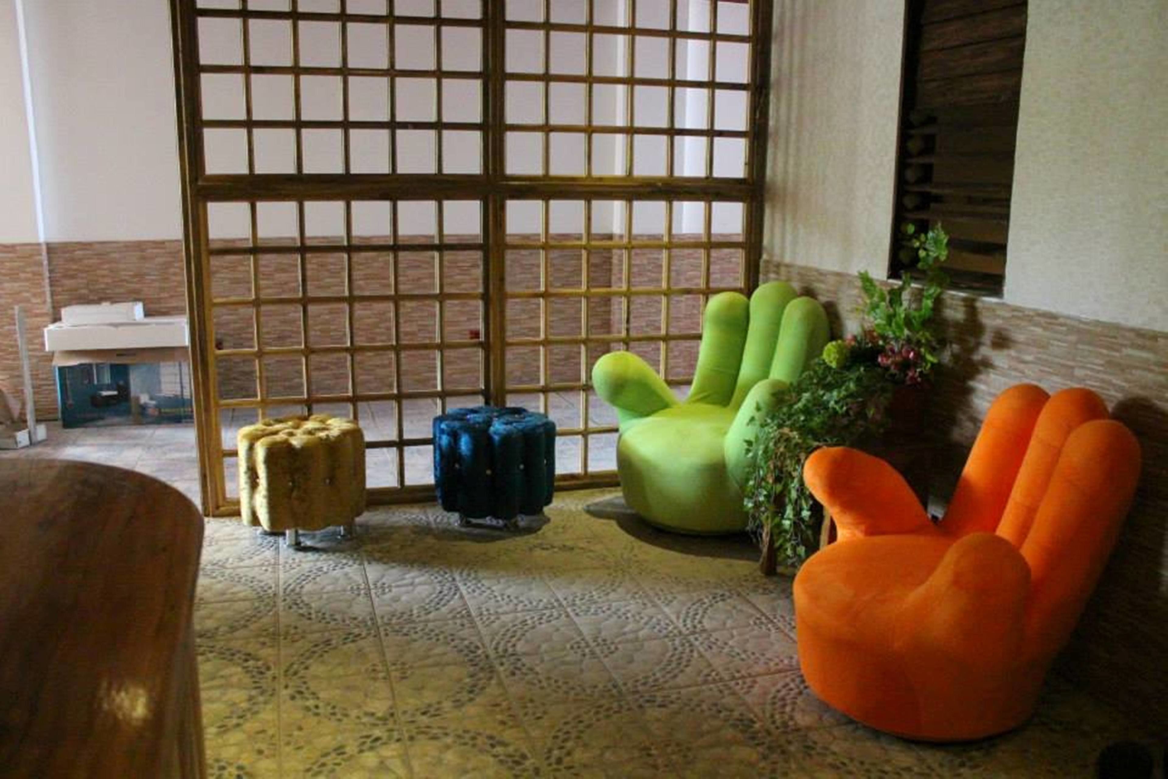 A room with a patterned floor, a green chair, a blue ottoman, and an orange chair.