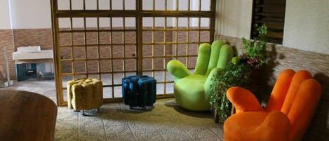 A room with a patterned floor, a green chair, a blue ottoman, and an orange chair.