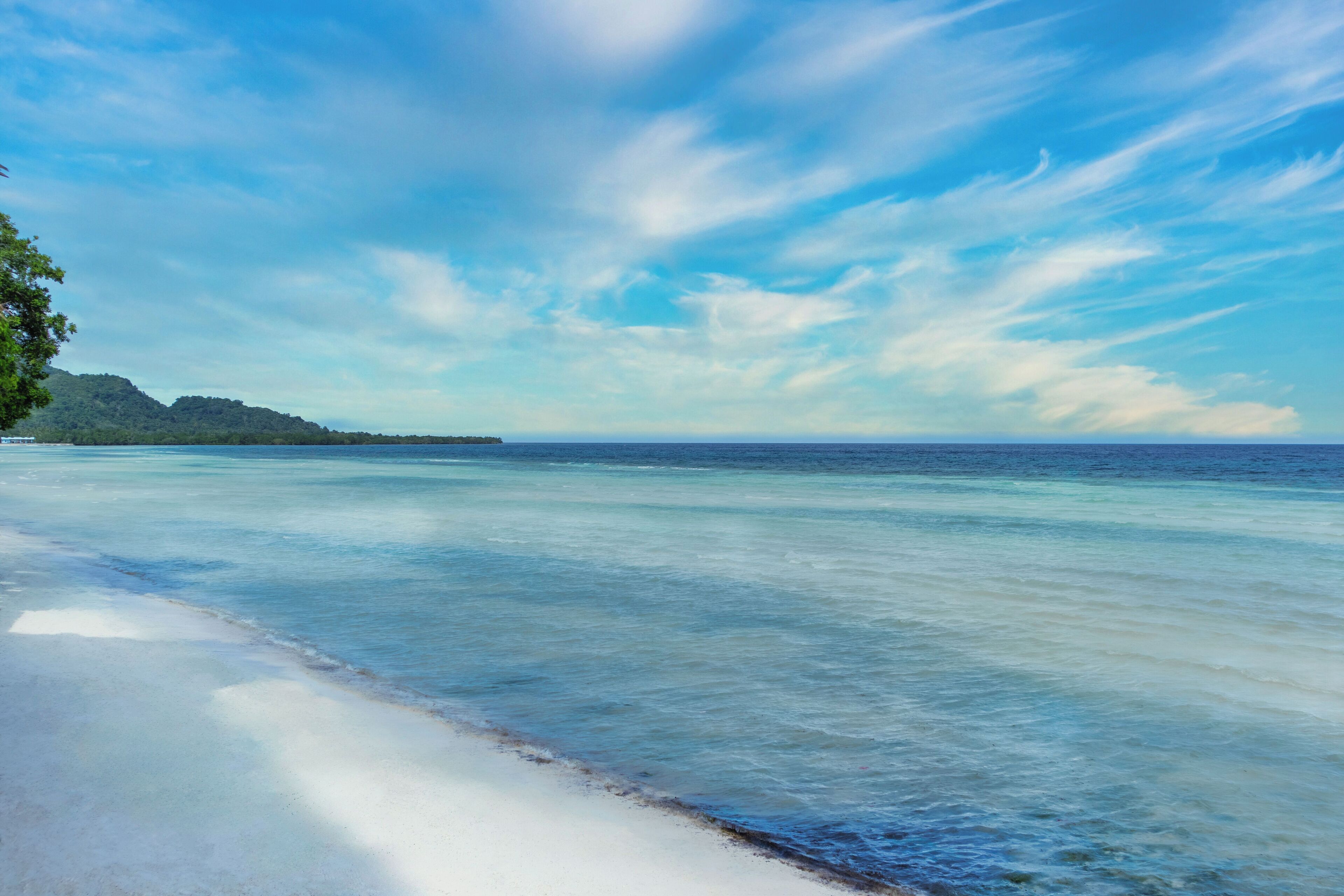 A beach with clear water, a sandy shore, and a distant landmass.