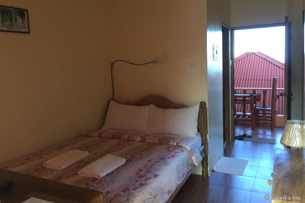 Un dormitorio con una cama, cabecero de madera, mesita de noche y una ventana.
