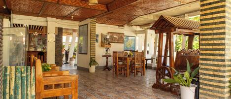 A spacious room with a tiled floor, wooden furniture, and a ceiling with a woven pattern.